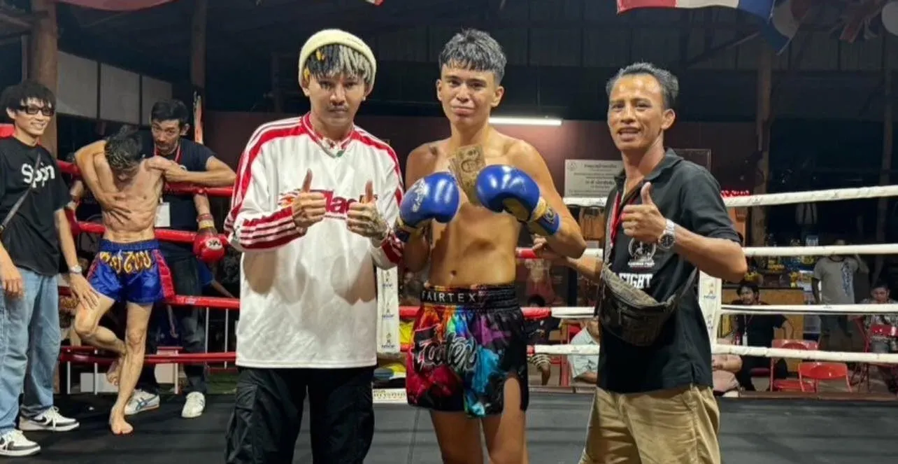 Winner of a Muay Thai fight standing in the middle with his two coaches